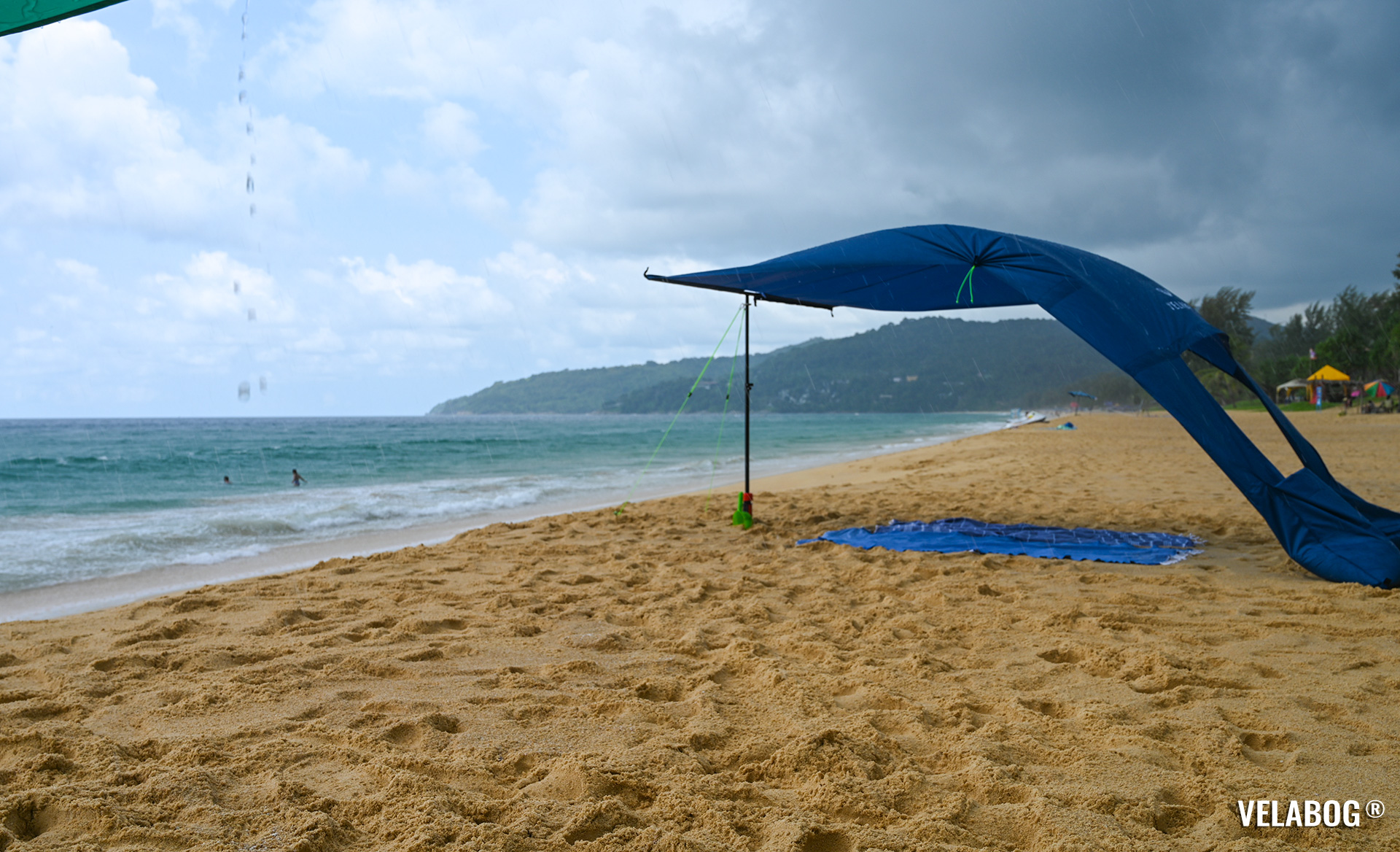 Beach sun sail Velabog Breeze, nightblue. Best beach sun canopy tent on the beach even during a rain shower. Setup option for light to strong wind. View from the side.