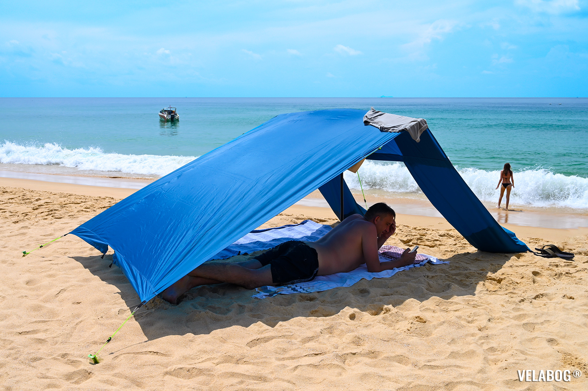 Beach sun sail Velabog Breeze, blue. Best beach sun canopy tent, airy sun shelter on the beach in Thailand. Setup option for no, light or gusty wind. Side view.