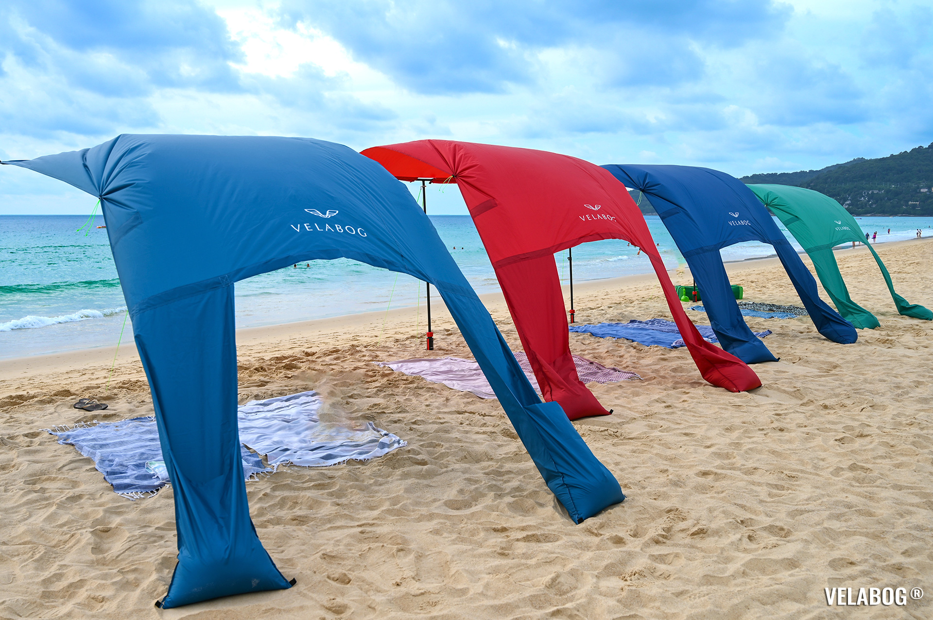 Four beach sun sails Velabog Breeze as airy sun shelters on the beach, best beach sun canopy tent. Setup option for light to strong wind. View from behind.