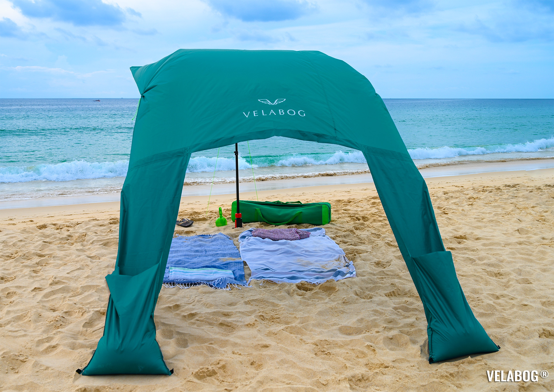 Beach sun sail Velabog Breeze, green, on beach in Thailand. Best beach canopy tent, high and airy sun shelter on the beach. Setup option for light to strong wind. View from behind.