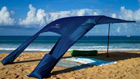Beach sun sail Velabog Breeze, nightblue, on the windy beach. Best beach canopy. Beach sun sail, beach umbrella and beach tent in one. Very large and yet compact. View from behind.
